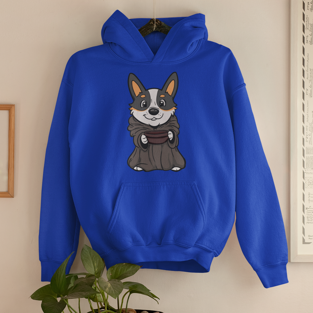 A blue hoodie hanging by a hanger on a cream painted wall. The hoodie is blue and has a tricolor corgi dressed up as Grogu, baby yoda. 