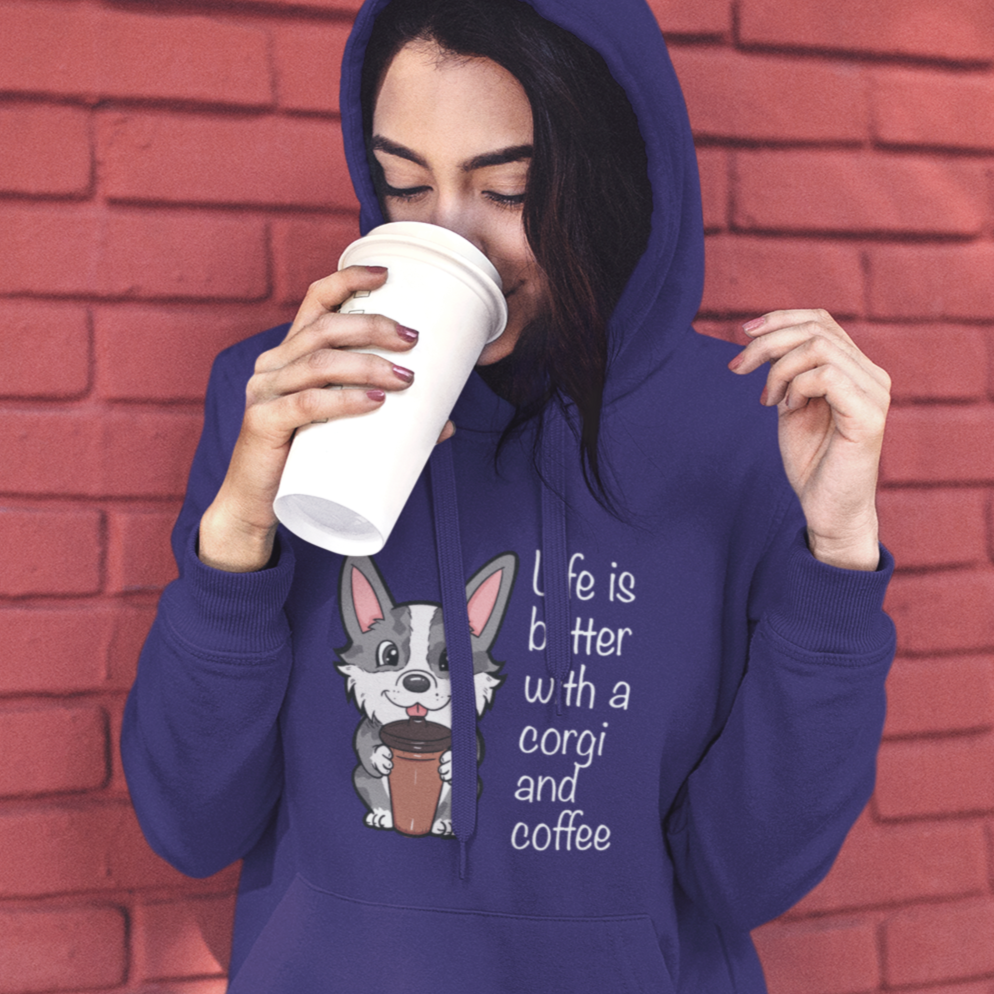 A model is drinking from a travel coffee cup and wearing wearing a hoodie with a cardigan corgi holding a cup of coffee. The text says "Life is better with a corgi and coffee". The sweatshirt is purple.