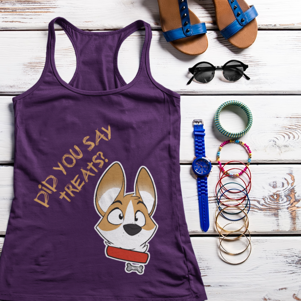 A flat lay of a racerback tank top among some summertime accessories like bracelets, sunglasses, and sandals. The design on the tank top has text "Did you say treats" with a corgi's face next to the text. The tank top is purple.