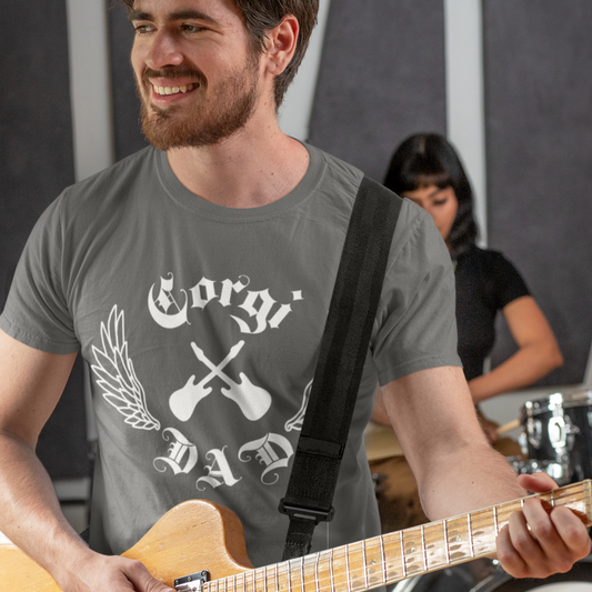 A man playing a guitar and is wearing a dark grey t shirt with a white design of: crossed electric guitars, lined wings, and text that says "Corgi Dad" in old english font. 