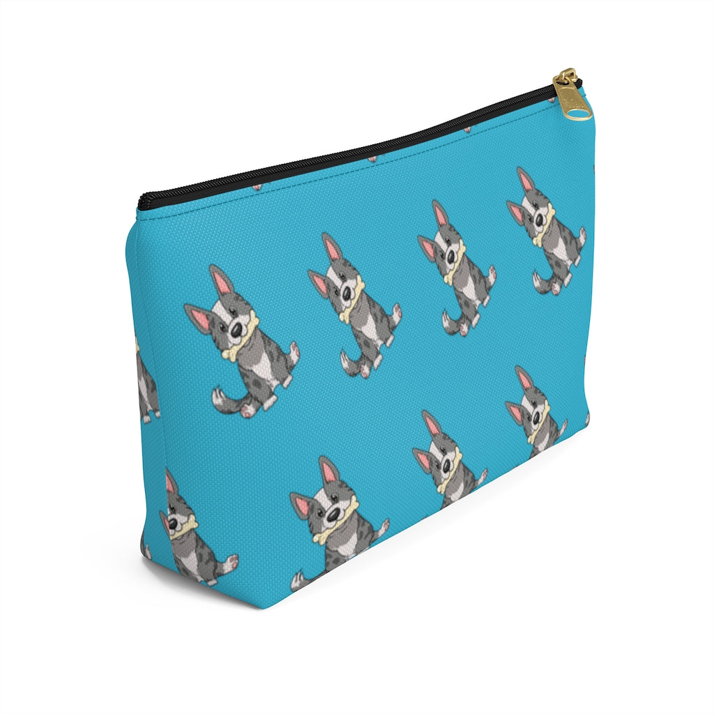 Blue make up bag with a pattern of a cardigan corgi holding a bone in its mouth, with black zipper, view from the side