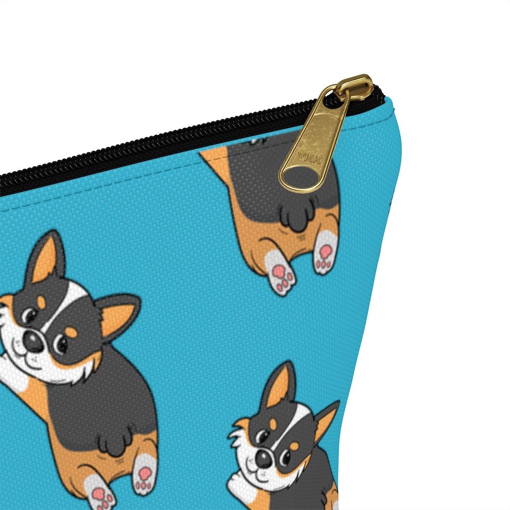 A blue make up bag with a pattern of a tricolor corgi splooting.