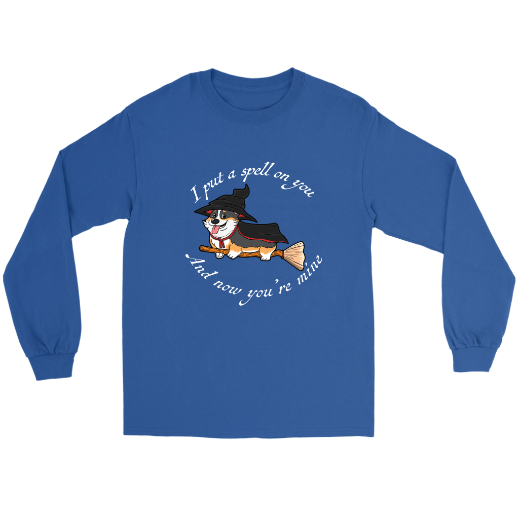 A flat lay of a long sleeved t shirt. The shirt is blue and has white text that says: I put a spell on you and now you're mine. There is also a tricolor corgi dressed as a witch while riding a broom. 