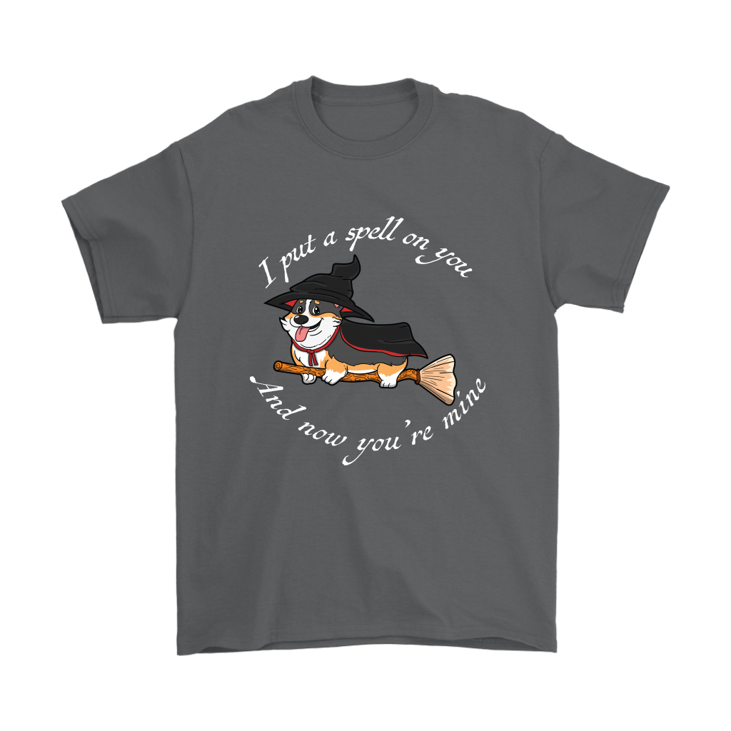 A t shirt with a tricolor corgi wearing a witch costume while riding a broom. The text says "I put a spell on you and now you're mine" and the shirt is charcoal colored.