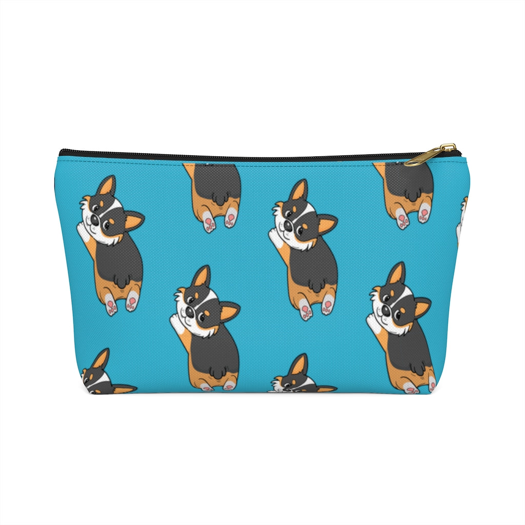 A blue make up bag with a pattern of a tricolor corgi splooting.