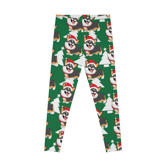 A flat lay of a green pair of leggings. The pattern on the leggings is a white Christmas trees and a tricolor corgi wearing a Santa hat. 