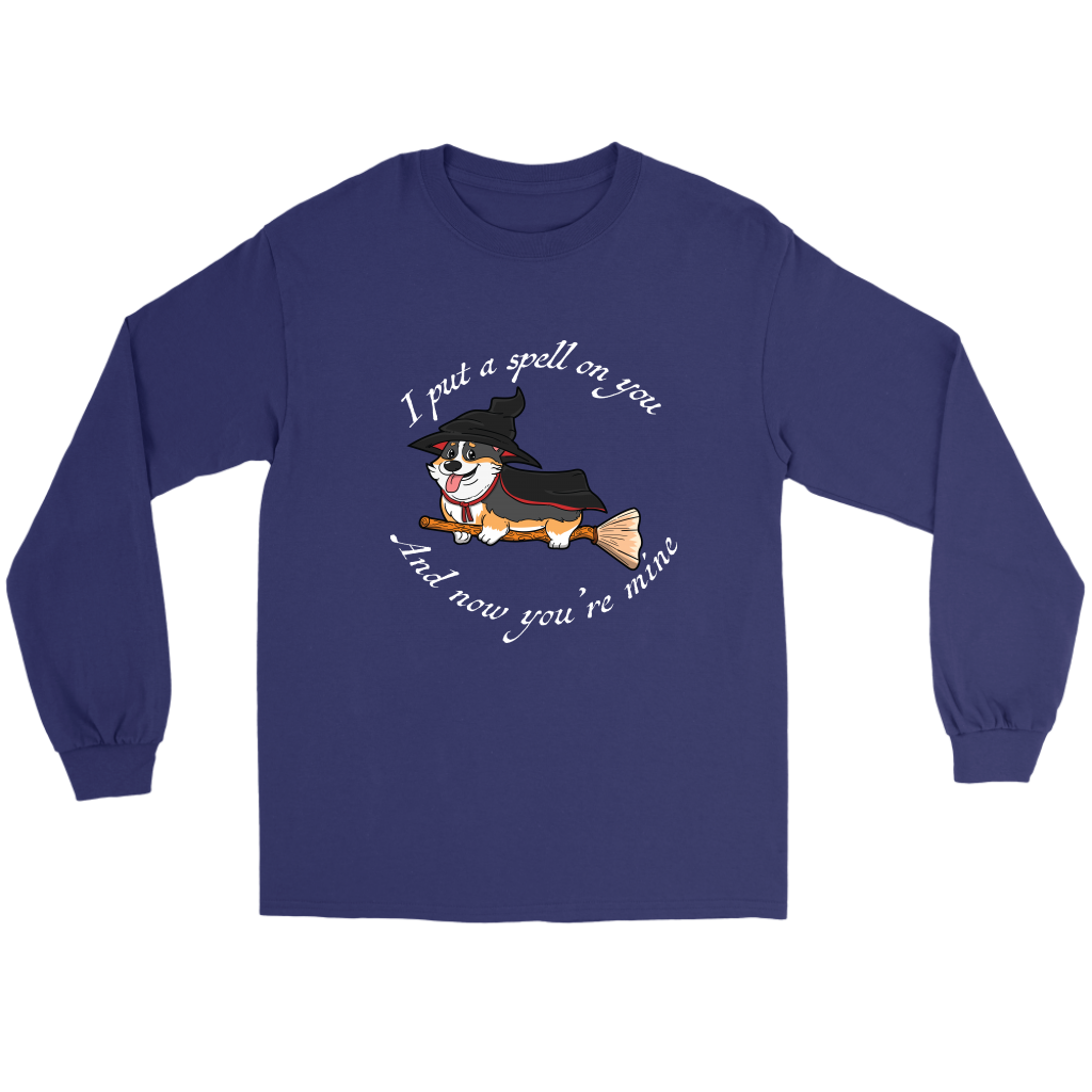 A flat lay of a long sleeved t shirt. The shirt is dark blue and has white text that says: I put a spell on you and now you're mine. There is also a tricolor corgi dressed as a witch while riding a broom. 