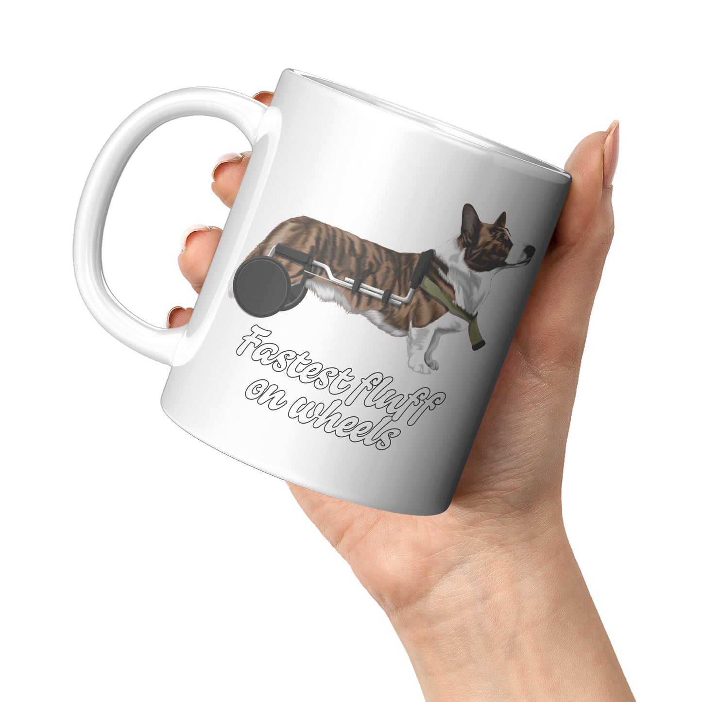 A hand holding a white mug. The design of the mug is a cardigan corgi in a wheelchair. The text says "Fastest fluff on wheels".