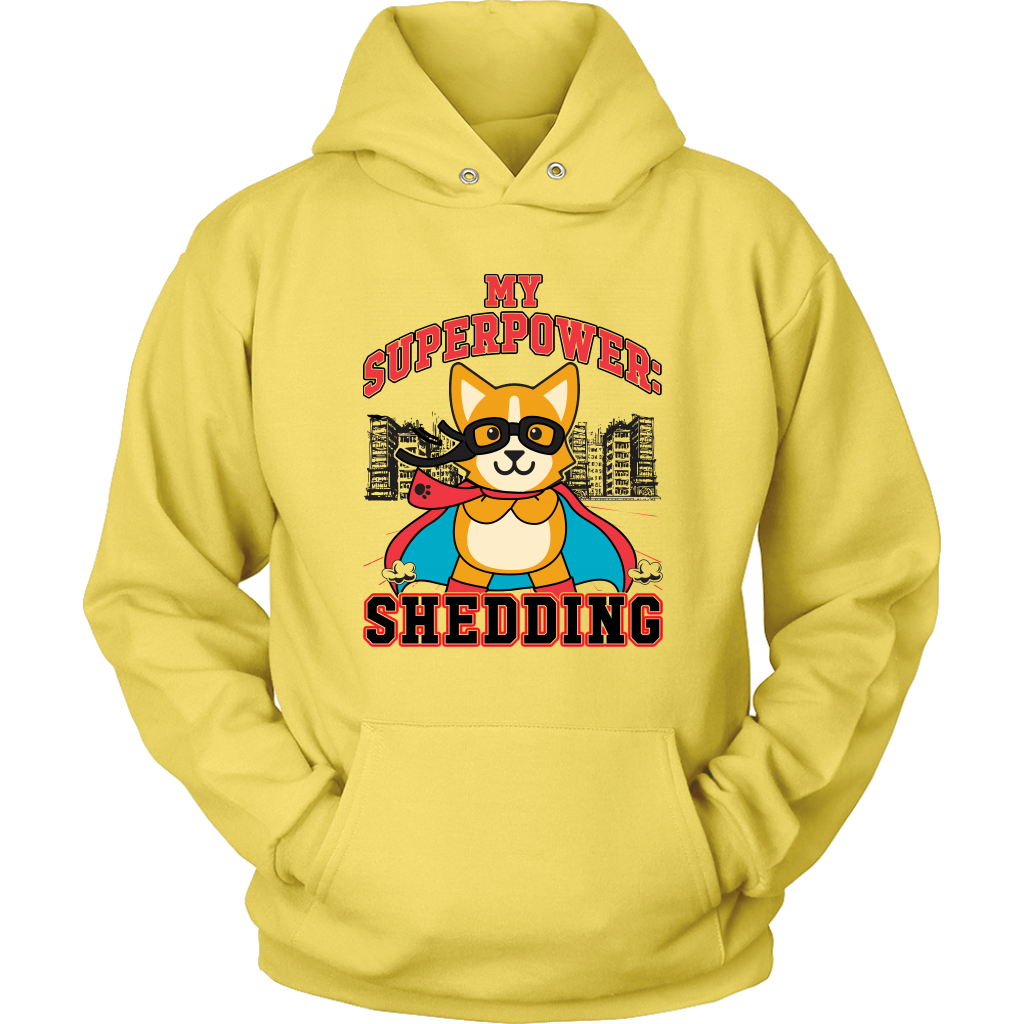 A flay lay of a hoodie that is yellow and has red and black text that says "My superpower: Shedding" with a corgi dressed as a superhero. 