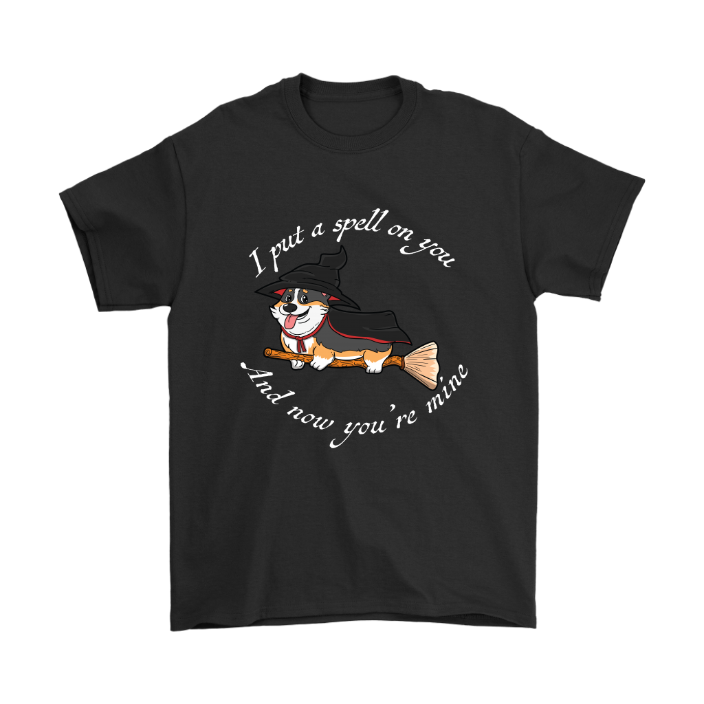 A t shirt with a tricolor corgi wearing a witch costume while riding a broom. The text says "I put a spell on you and now you're mine" and the shirt is black.