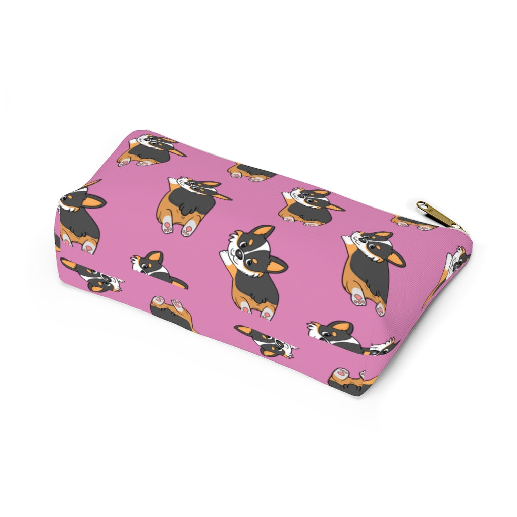 A pink make up bag with a pattern of a tricolor corgi splooting.