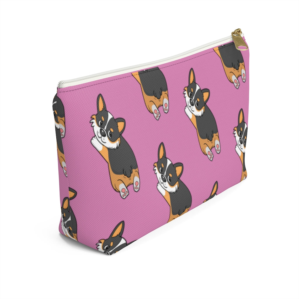 A pink make up bag with a pattern of a tricolor corgi splooting.