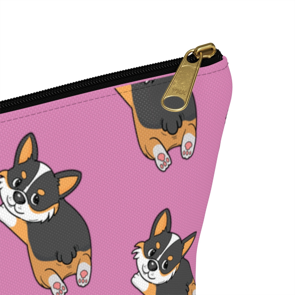 A pink make up bag with a pattern of a tricolor corgi splooting.