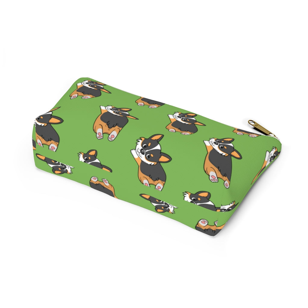 A green make up bag with a pattern of a tricolor corgi splooting.