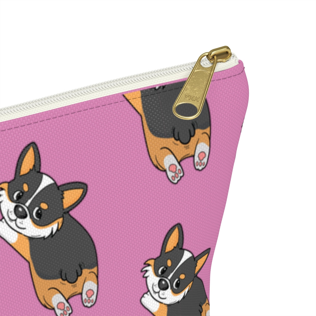 A pink make up bag with a pattern of a tricolor corgi splooting.