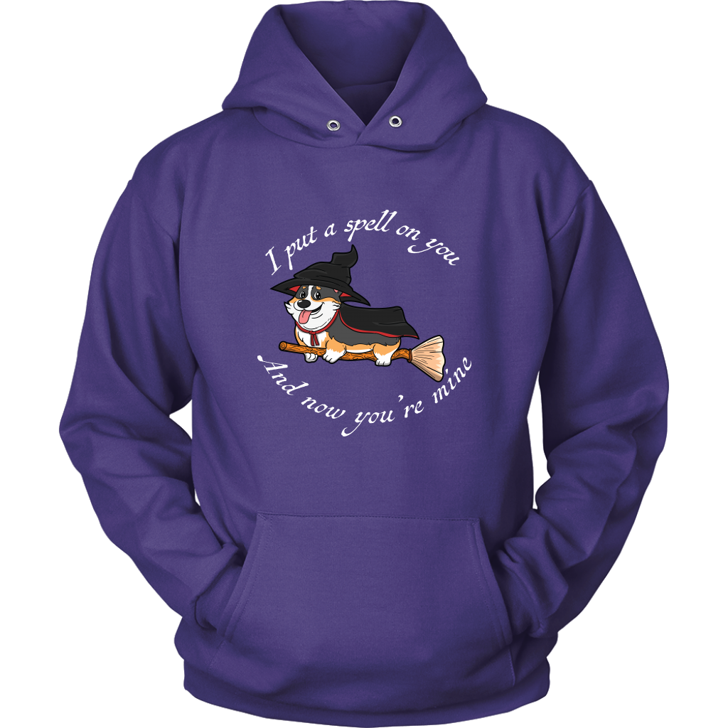 A hoodie with a corgi dressed as a witch with the text "I put a spell on you and now you're mine". The hoodie is purple. 