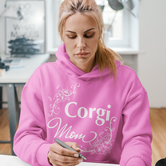 A model wearing a hoodie with the text "Corgi Mom" and flower line designs. The hoodie is pink. 