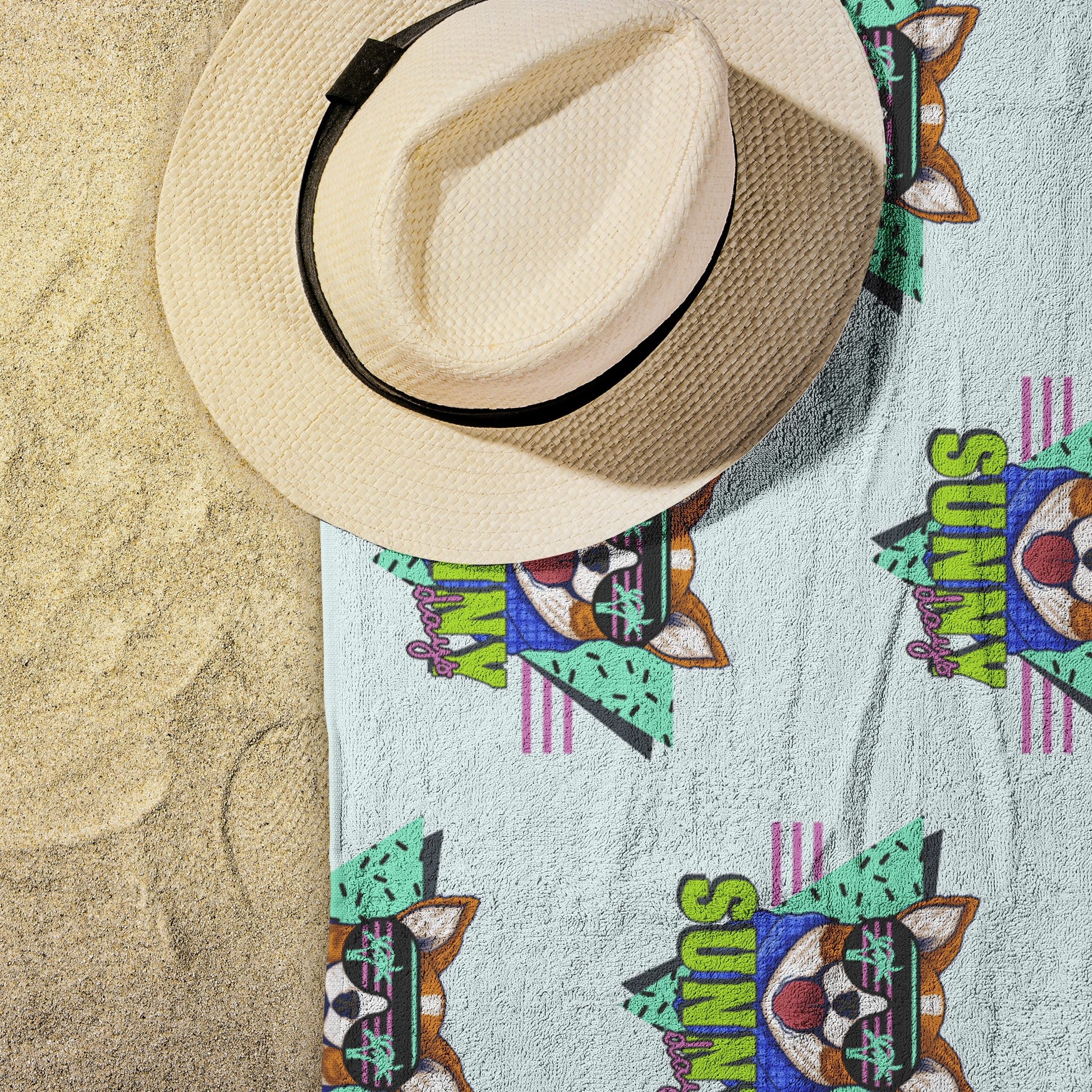 The sunny days beach towel on some sand with a hat on the corner.