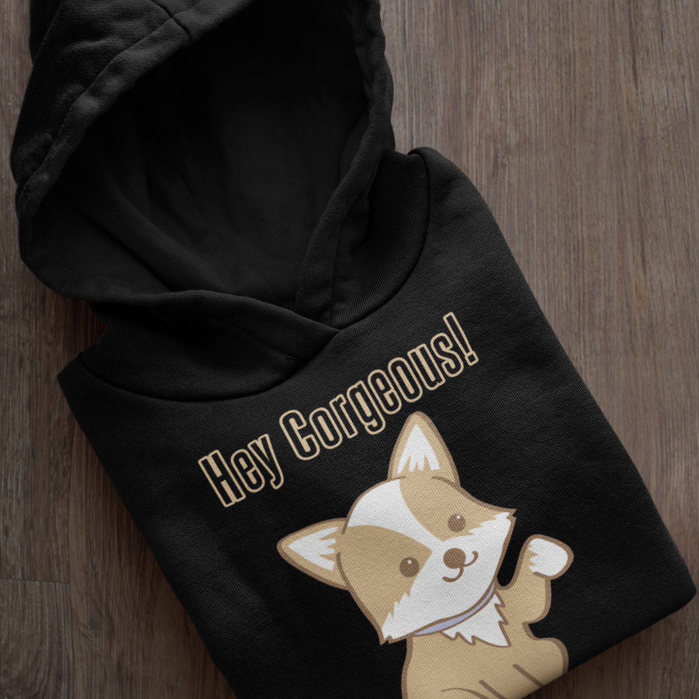 A folded up hoodie with the text "Hey Corgeous!" and a waiving corgi. The hoodie is black. 