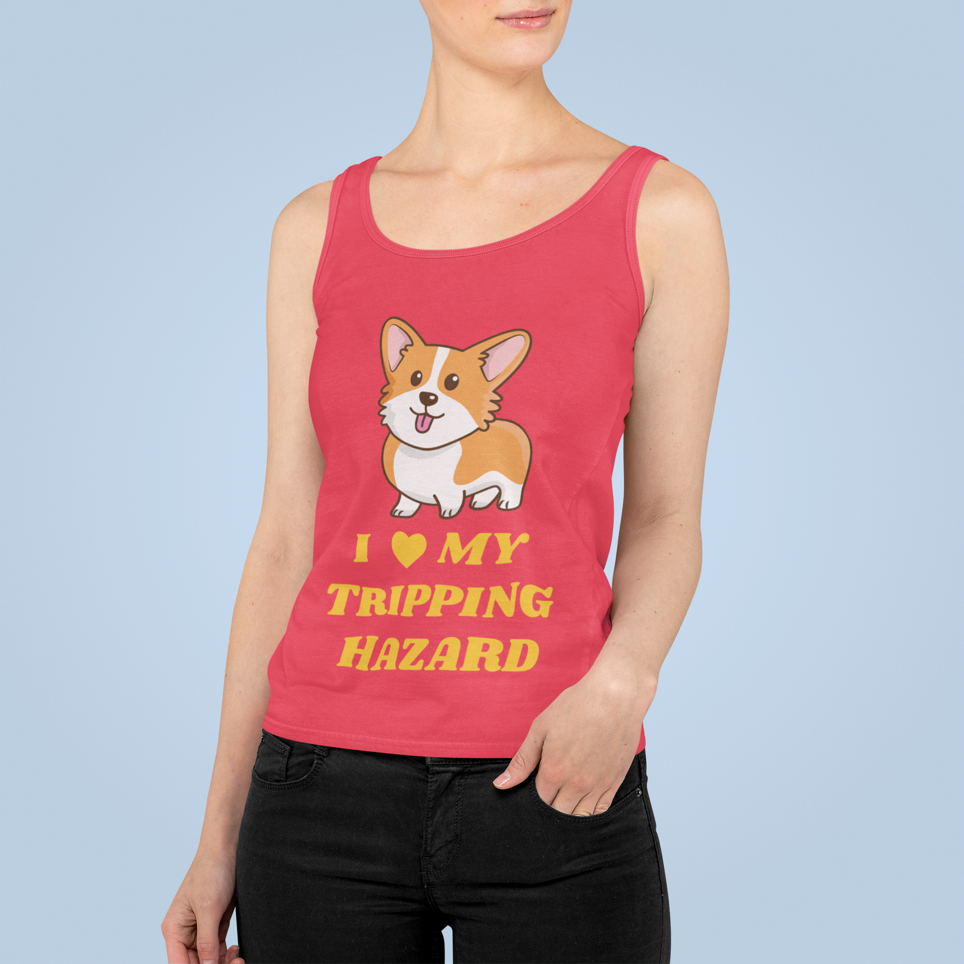 A model wearing a racerback tank top with the text "I love my tripping hazard" with a picture of a corgi. The tank top is red.