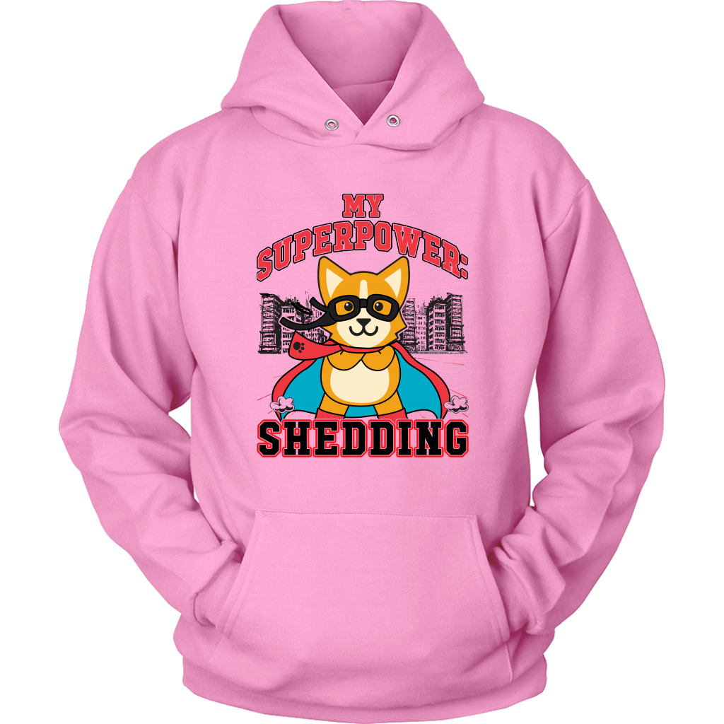 A flay lay of a hoodie that is pink and has red and black text that says "My superpower: Shedding" with a corgi dressed as a superhero. 