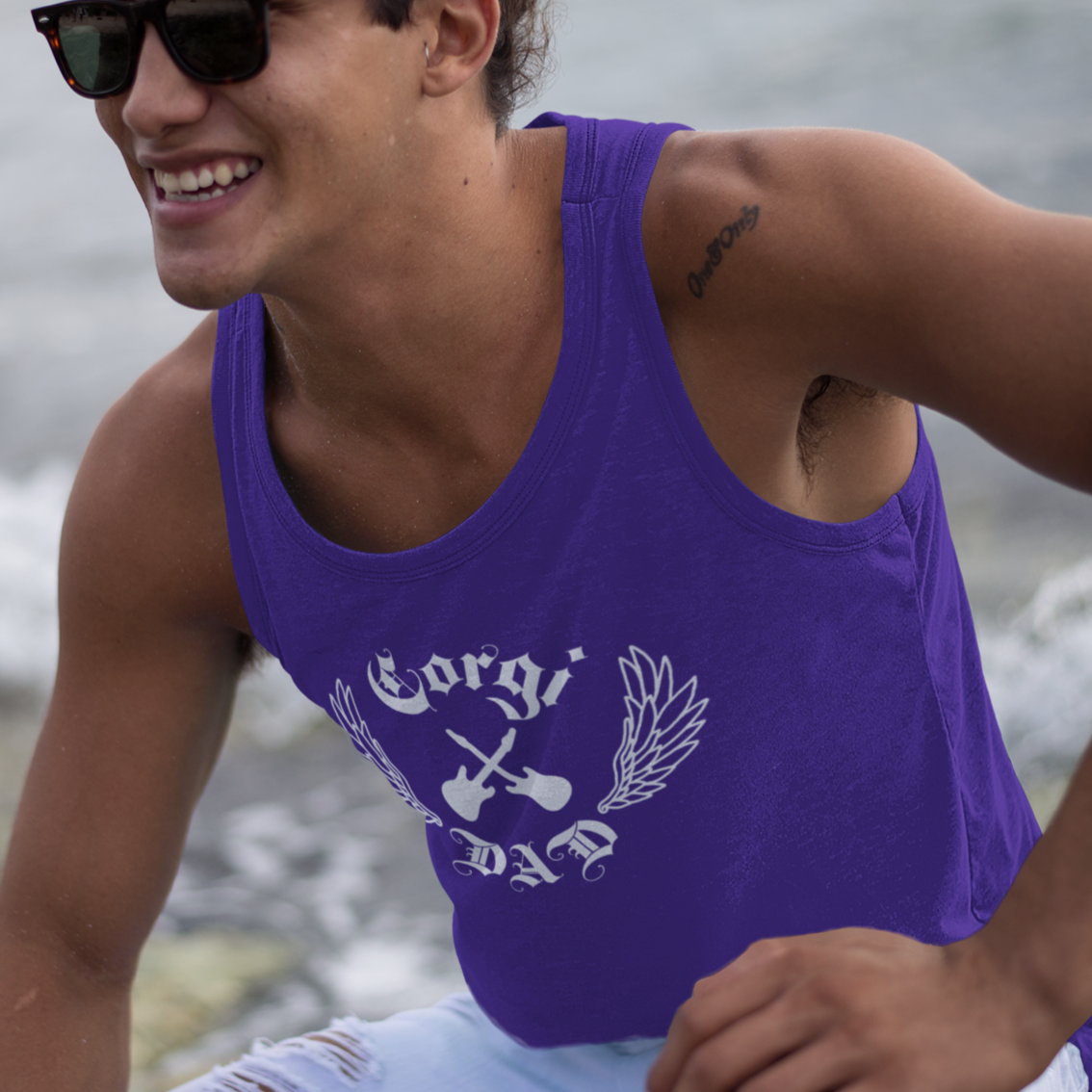 A model wearing a purple tank top that says "Corgi Dad" with crossed guitars and wings. 